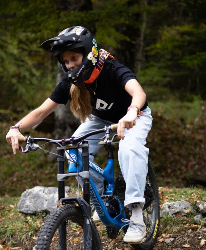 Hoodie noir Fearless Flow pour rider VTT freeride, porté par l’ambassadrice Mathilde qui descend sur son DH Commencal au bike park, vue de dos.