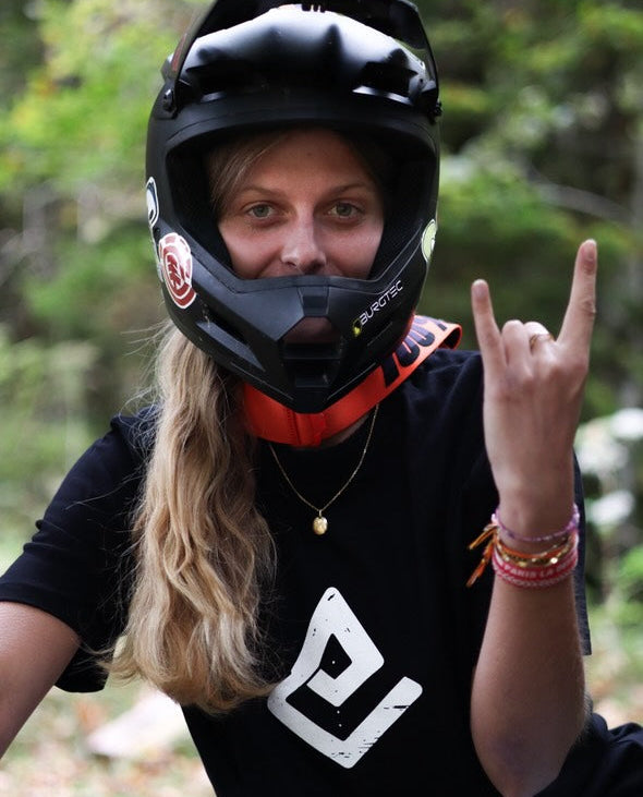 Hoodie noir Fearless Flow pour rider VTT freeride, porté par l’ambassadrice Mathilde sur son DH Commencal au bike park, vue de face.