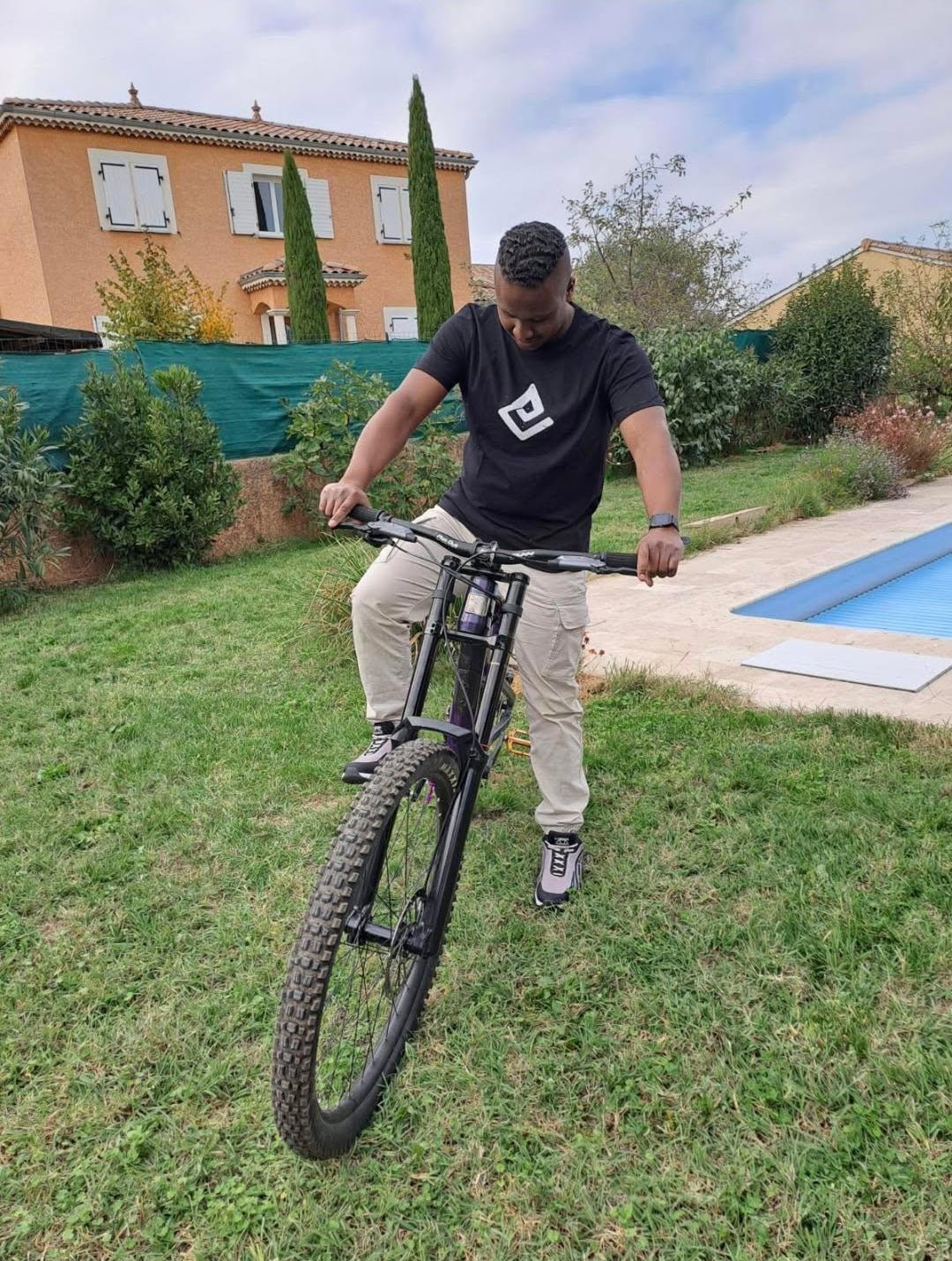 Hoodie noir Fearless Flow pour rider VTT freeride, porté par l’ambassadeur Corentin assis sur son DH Marin violet, vue de face.