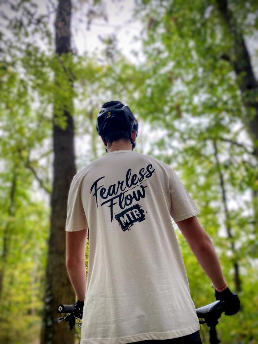 Tee-shirt écru Fearless Flow pour rider VTT freeride, porté par l’ambassadeur Mathis, vue de dos avec inscription noire.