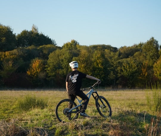 Tee-shirt noir Fearless Flow pour rider VTT, freeride, vue de dos impression blanche, porté par l'ambassadeur Martin, assis sur son VTT.